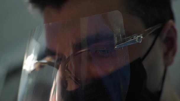 一位英俊的男性身体学家在工作时的面部保护屏风中的面部特征的特写 牙医治疗牙齿 男性牙医的概念 专注的眼神 医生的眼睛 — 图库视频影像