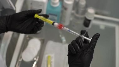 Güzellik uzmanında iki birleşik şırınga var, doktor. Siyah lateks eldivenli doktor estetik ameliyattan önce hazırlanır. Kapat..