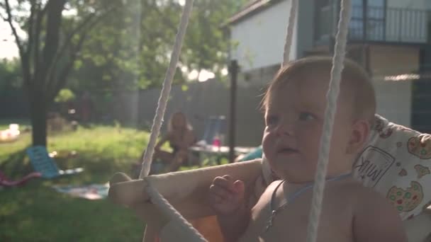 Zwolnij Trochę Małe Słodkie Dziecko Niebieskimi Oczami Jeździ Huśtawce Ogrodzie — Wideo stockowe