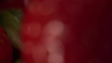 Kırmızı olgun bir çilek dönüşünün yakın çekimi. Bulanıklıktan odaklanmaya. Çilek yüzeyinde büyük taneler görebilirsiniz.
