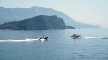 Adriyatik Denizi 'nde, dağların arka planında, iki tekne ve motorlu tekne birbirine doğru ilerliyor. El bilgisayarı atışı