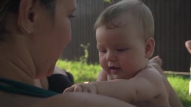 Mutlu bir aile. Sevimli bebek elleri. Annem kızına bahçede sarılıyor. Yazın, ilkbaharda bir kır evinde. Annem kucağında bir bebekle oynuyor. Boynunda haç.