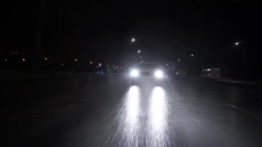 Ukrayna, Zaporozhye - 25 Aralık 2022: araba asfalt yolda yüksek hızda sağanak yağmurda gece yol alıyor. Işıklar yağmurda parlıyor. Ön tampondaki far görünümlü arabadan bir ışık demeti.