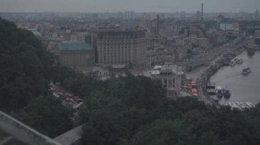 Şehrin kuş bakışı manzarası, köprüde araba trafiği, gökdelenlerin inşası, rıhtımda yürüyen insanlar, eğlence gemilerinin ve teknelerin olduğu yerler. gri yaz günü
