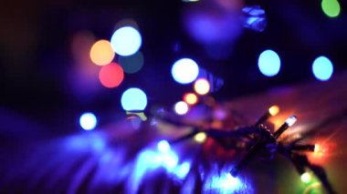 Yüzen odak, önden arkaya doğru. Yılbaşı arkaplanında, karanlığın içinde Noel, toplar, oyuncaklar ve çelenklerin çok renkli yanıp sönen ışıkları. yakın plan
