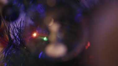 Yeni yıl oyuncağının pürüzsüz yakın çekimi, cam küredeki kutup ayısına odaklan, arkasında bir çelenk ve toplar görünür.