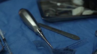 Genel anestezi altında yirmilik dişli hastayı çıkarmak için ameliyat masasında cerrahi diş aletleri. Diş çekilmesi. Kanlı neşter. Kemik nakli, yerleştirme diş implantları.