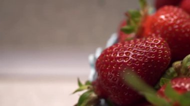 Yatay kamera hareketi. Makro, doku, sulu, taze çilek. Bir sepet dolusu çilek. Göz kamaştırıcı. Gri arka planda, mutfakta.