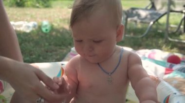 Hristiyan haçı. Bebek sıcak bir yaz gününde bir çocuk havuzunda oturuyor. Anne onun üzerine su dökerken bebek merakla etrafına bakıyor, onu zevkten kıkırdatıyor. Yavaş çekim