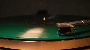 Yeşil bir vinil plak plağı çalıyor. İğne tabakta sorunsuzca süzülür, müzik çalar. yakın plan.
