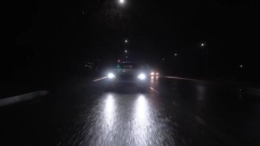 Gece yağmurda beyaz bir çapraz araba otoyol boyunca yavaşça gider, bir sonraki şeride yeniden inşa eder, kötü hava, sonbahar, soğuk