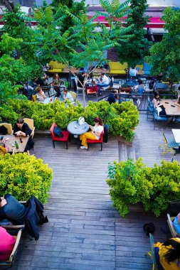 İnsanlar restoranın bahçesinde yemek yiyor.