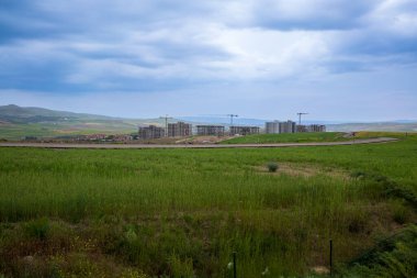 Uzakta yeşillikler arasında toplu konut inşaatı görülüyor