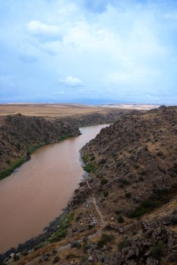 Nehir yağmurdan bulanık, kanyondan akıyor.