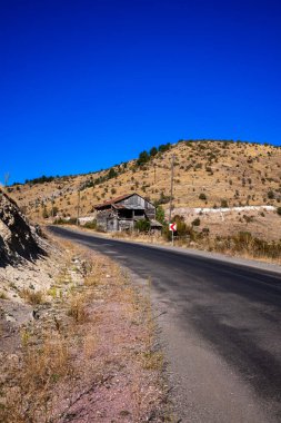 Arka planda mavi gökyüzü olan güzel bir dağ manzarasına giden yol..