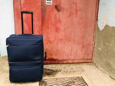 Bir bavul kırsal bir kapının yanında duruyor, yolculuğa hazır..