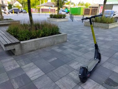 Scooter sakin bir şehir meydanında kaldırımda dinleniyor..