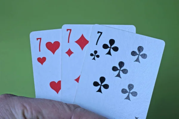 Handen Innehar Tre Spelkort Med Sjuor Grön Bakgrund — Stockfoto