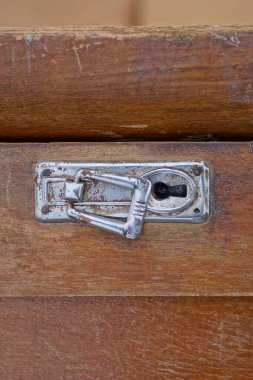 Bir deponun kahverengi ahşap kapısında paslanmış eski bir gri metal anahtar deliği.