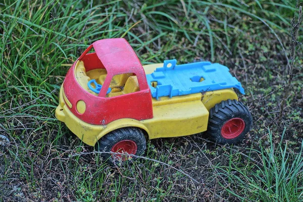 Jeden Plastikowy Kolorowy Samochód Zabawki Stoi Zielonej Trawie Szarym Gruncie — Zdjęcie stockowe