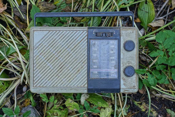 大自然的青草上躺着一台旧的脏塑料灰色黑色收音机 — 图库照片