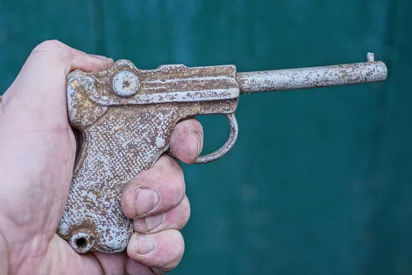 Ręka Trzyma Jeden Stary Szary Brudny Pistolet Aluminiowy Zabawka Zielonym — Zdjęcie stockowe