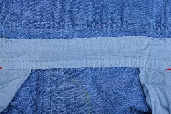 ブルーのコットン生地に白い縫い代をつけた服の質感 — ストック写真
