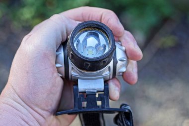 Elinde gri siyah plastik bir far vardı.