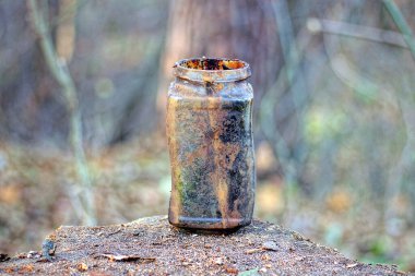 Kirli, siyah, kahverengi, eski bir kavanoz caddedeki ahşap bir masada duruyor.