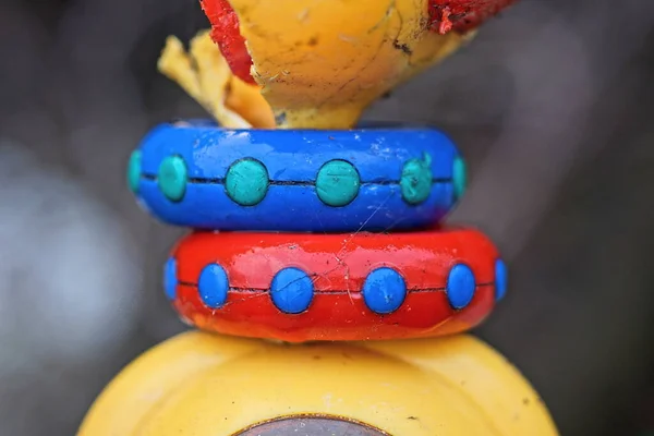 part of a plastic toy with colored rings on a gray background
