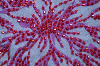 Küçük boncuklu ve desenli bir madde parçasından kırmızı beyaz kumaş dokusu