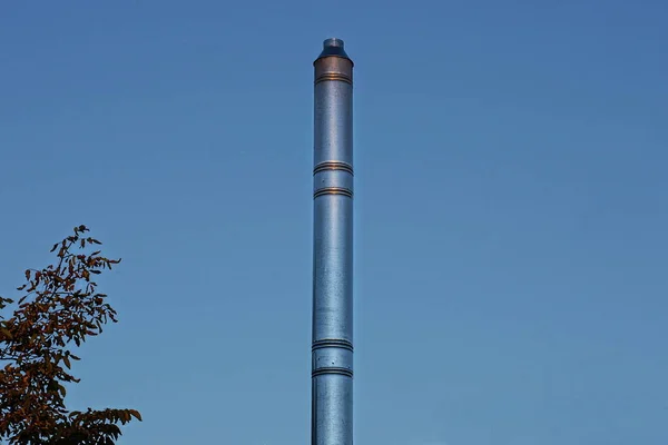 青い空に背の高い灰色の金属製の煙突のパイプが — ストック写真