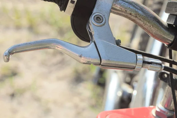 自転車のハンドルバーの一部に白い金属製のハンドブレーキとケーブルがついています — ストック写真