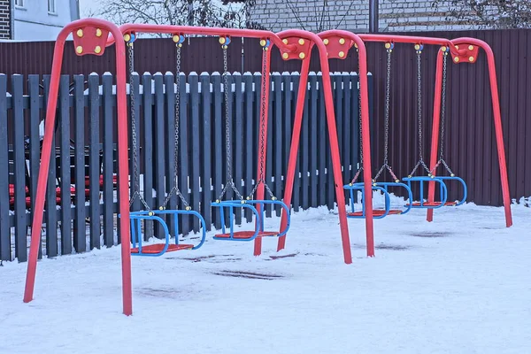 Два Пустых Красных Металлических Качели Детской Площадке Белом Снегу Зимней — стоковое фото
