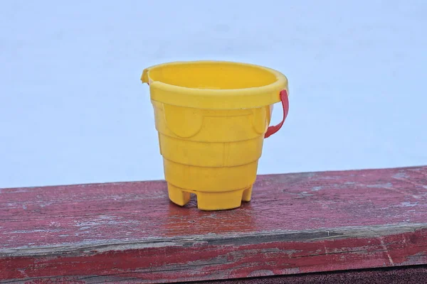 Juguete Cubo Plástico Amarillo Está Parado Una Mesa Madera Roja — Foto de Stock