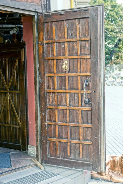open old brown wooden door on the wall of a building on the street