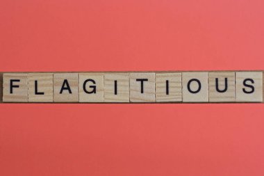 text the word flagitious from gray wooden small letters with black font on an red table