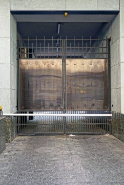 one big black iron gate on a gray stone wall of a building on a city street