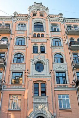 part of a brown white stone wall of an old historical building with windows on a city street