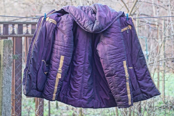 one purple winter jacket made of fabric hanging on a wire in the street