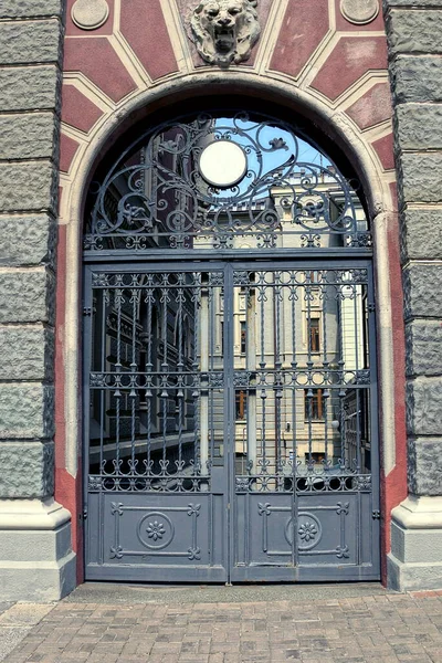 one big black iron gate on a gray stone wall of a building on a city street