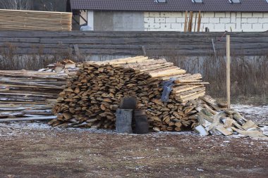 a pile of brown wooden boards lie on gray ground in a rural street