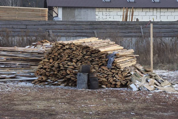 a pile of brown wooden boards lie on gray ground in a rural street
