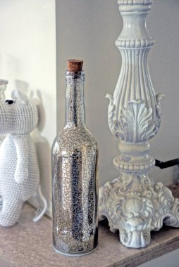 one gray decorative glass closed bottle stands on a brown table against a white wall in the room