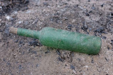 garbage from one dirty old glass green bottle lies on the gray ground on the street