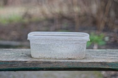 one white dirty plastic box stands on a gray wooden table in the street