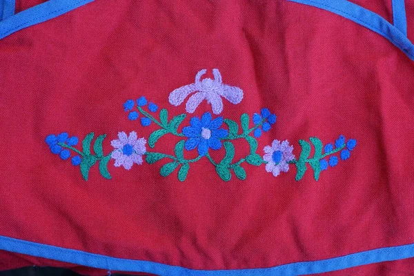 a patch of embroidered colored flower patterns on red fabric on clothes