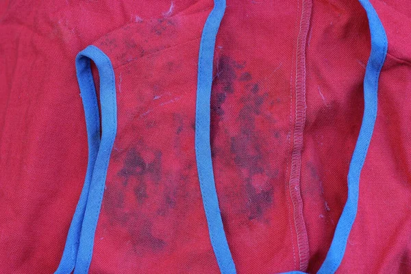 red fabric texture from old matter with gray dirty spots and blue seams on clothes