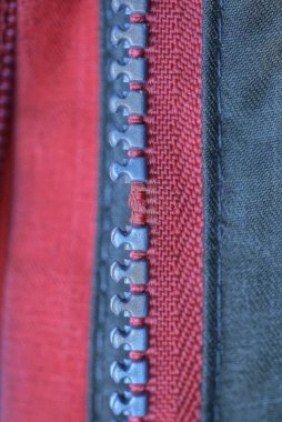 gray broken plastic zip on red green clothing fabric
