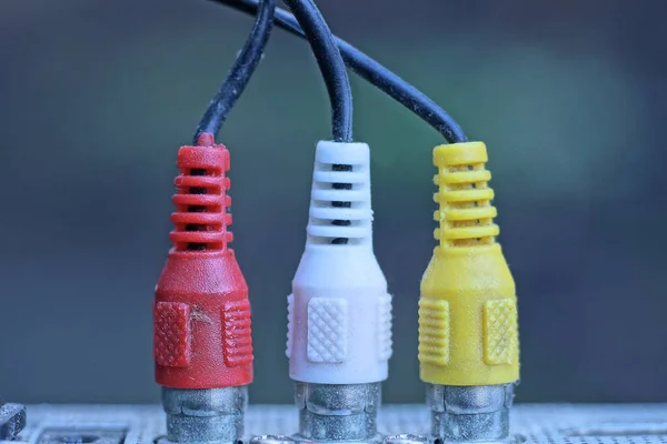 三个有线的彩色老插头与灰色背景的金属电气设备相连 — 图库照片